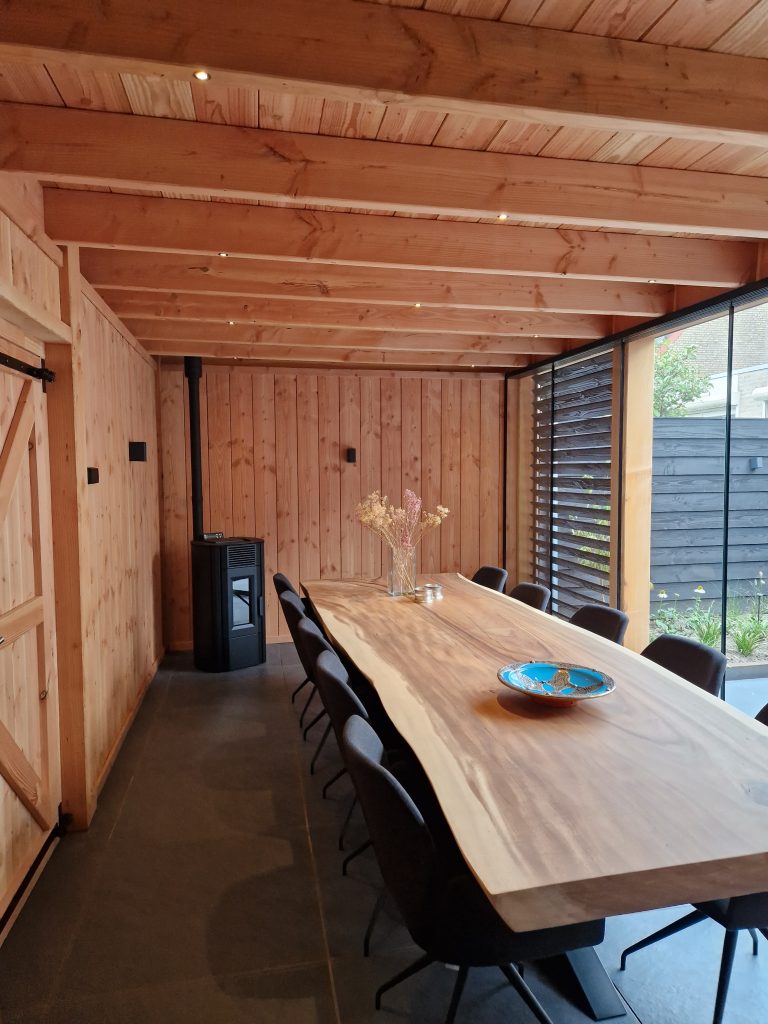 Douglas houten overkapping met binnen keuken, houtkachel, unieke houten tafel, shutters & glazenschuifpui
