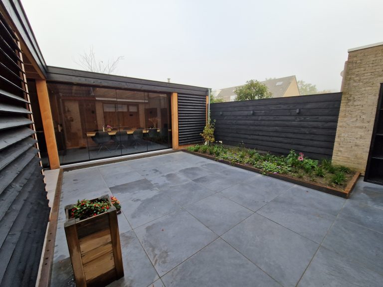 Achtertuin in Breda met keramische tegels 60x60 met cortenstalen opsluiting met daarachter beplanting + zweeds rabat schutting.
