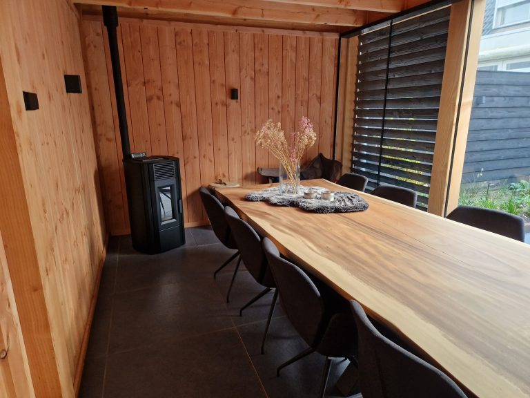Overkapping met houtkachel, unieke houten tafel, shutters & glazenschuifpui